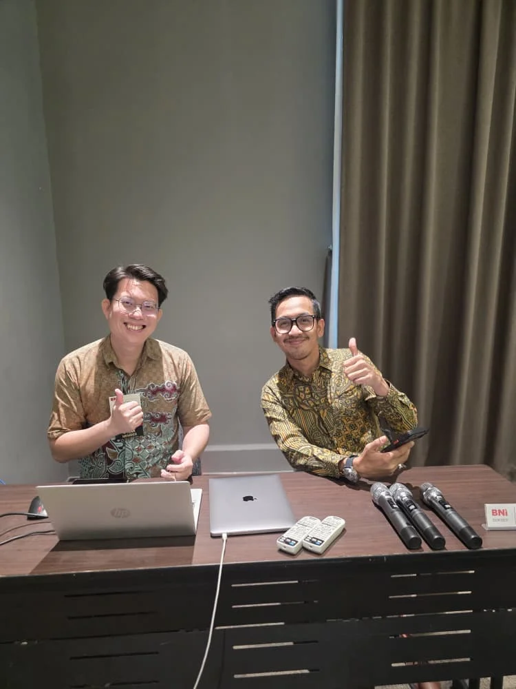 Dua peserta berbual di meja pertemuan